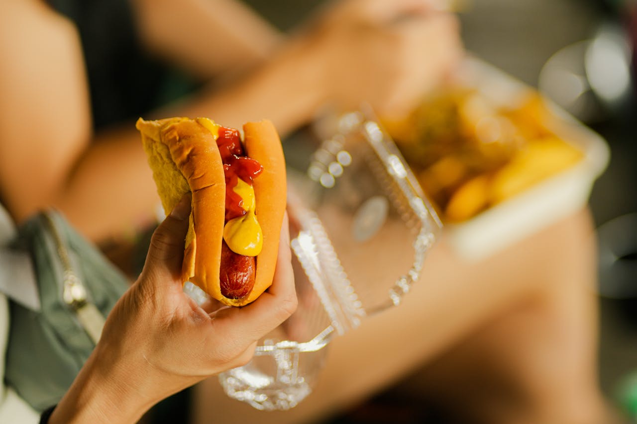 Services Close-up of a hot dog with mustard and ketchup held in hand, perfect street food meal.